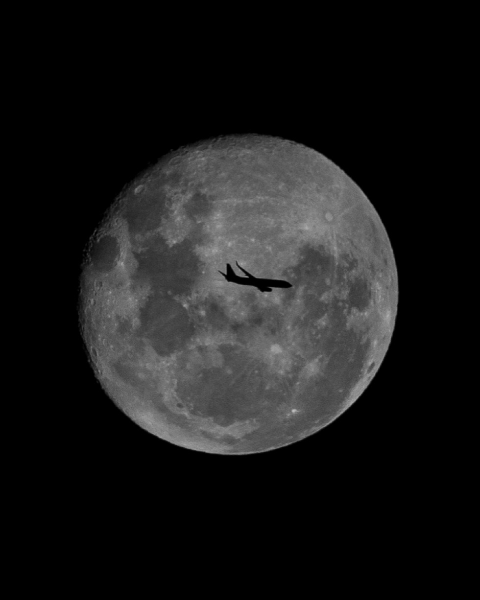 Airplane silhouette crossing the moon